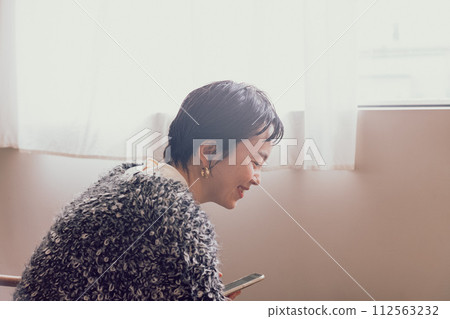 A stylish woman with a shortcut operating a smartphone with a smile A stylish woman with a shortcut operating a smartphone with a smile 112563232