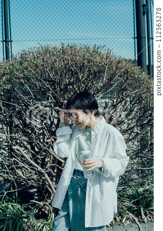 Stylish woman with a short cut hydrating outside 112563278