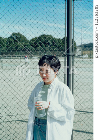 Stylish woman with a short cut hydrating outside Stylish woman with a short cut hydrating outside 112563285
