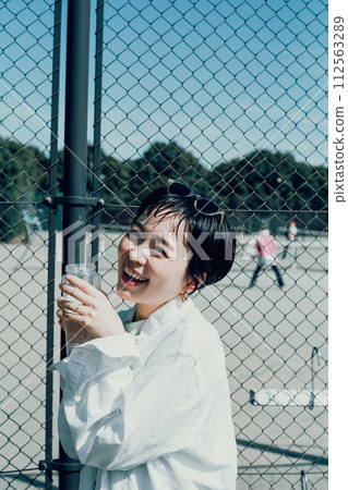 Stylish woman with a short cut hydrating outside Stylish woman with a short cut hydrating outside 112563289
