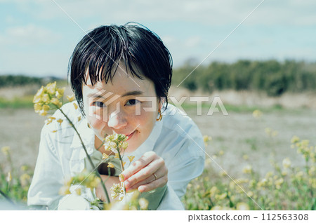 一位微笑的時尚女性,短髮,在外面欣賞鮮花 一位微笑的時尚女性,短髮,在外面欣賞鮮花 112563308
