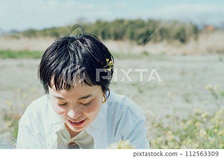 一位微笑的時尚女性,短髮,在外面欣賞鮮花 一位微笑的時尚女性,短髮,在外面欣賞鮮花 112563309