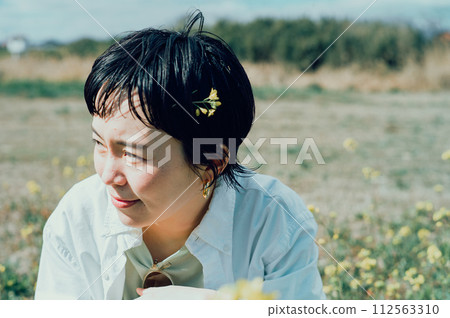 A smiling stylish woman with a short cut admiring flowers outside A smiling stylish woman with a short cut admiring flowers outside 112563310