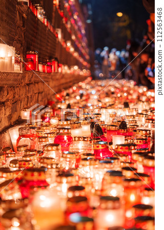 A solemn display of candles in glass jars lights up a pathway in Latvia, commemorating Independence Day with red hues symbolizing celebration and remembrance. A solemn display of candles in glass jars lights up a pathway in Latvia, commemorating Independence Day with red hues symbolizing celebration and remembrance. 112563468