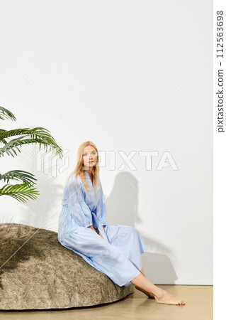 Blonde woman in summer dress sits on rock 112563698