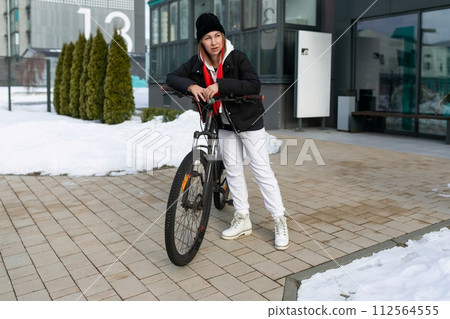 A woman went for a walk and took her bicycle with her in winter 112564555