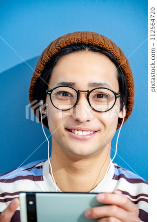 藍色背景和戴眼鏡的年輕人 112564720