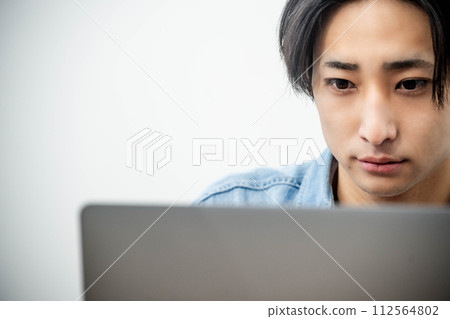 A young man working on a computer at the desk 112564802