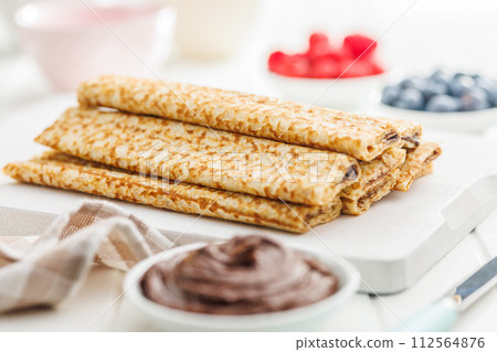Freshly Made Golden Crepes Stacked on a White Plate, Ready for Breakfast Freshly Made Golden Crepes Stacked on a White Plate, Ready for Breakfast 112564876