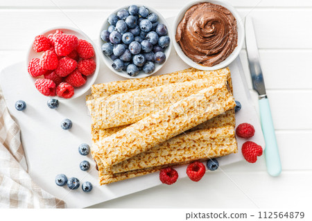 Freshly Made Crepes Topped With Raspberries and Blueberries on white table. Top view. 112564879