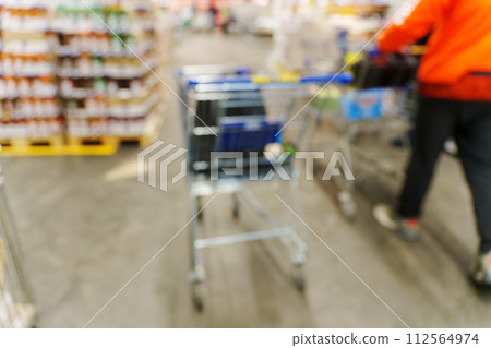 Blurry shot of a shopping cart in a busy store aisle, showcasing the hustle and bustle of shopping activities. 112564974