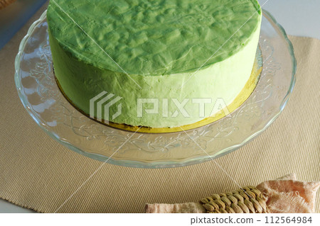 Green cake takes center stage on a glass plate, showcasing its vibrant hue and delicate elegance. 112564984