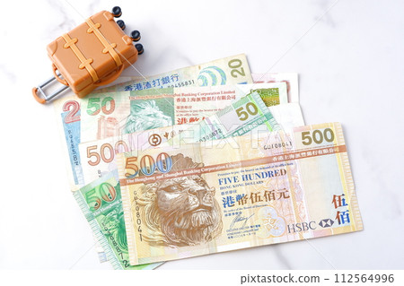 An image of a trip to Hong Kong with Hong Kong currency, Hong Kong dollar (HKD) banknotes and a suitcase. An image of a trip to Hong Kong with Hong Kong currency, Hong Kong dollar (HKD) banknotes and a suitcase. 112564996