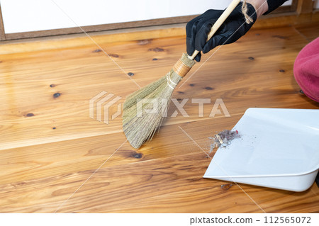 A scene where the collected garbage is placed on a dustpan using a small broom 112565072