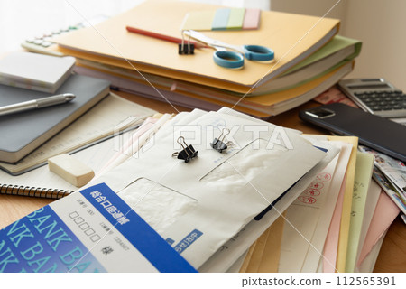 辦公桌上堆滿了堆積的文件和郵件,辦公桌凌亂,零散 辦公桌上堆滿了堆積的文件和郵件,辦公桌凌亂,零散 112565391