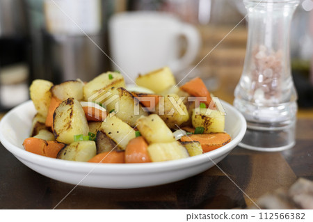 Roasted potatoes with carrot, onion, herbs and spices. Potato wedges with herbs. Roasted potatoes with carrot, onion, herbs and spices. Potato wedges with herbs. 112566382
