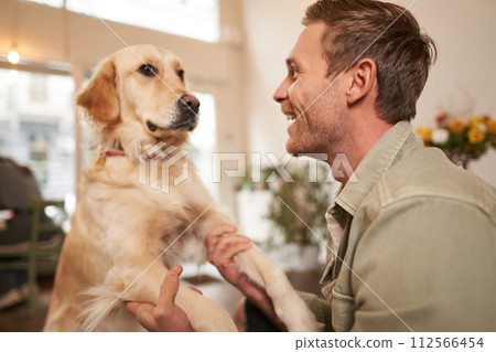 Close up portrait of cute dog and happy man, guy hugging his pet, spending time in animal-friendly cafe, waiting for an order Close up portrait of cute dog and happy man, guy hugging his pet, spending time in animal-friendly cafe, waiting for an order 112566454