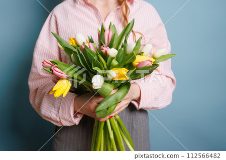 girl with a spring bouquet of tulips on a clean blue background, spring flowers girl with a spring bouquet of tulips on a clean blue background, spring flowers 112566482