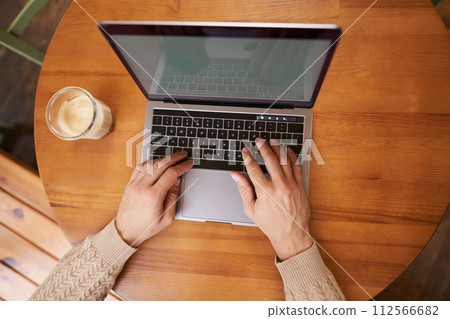 Portrait of male hands, laptop and cappuccino. Man typing on keyboard, working in cafe and drinking coffee, close up of computer screen and arms Portrait of male hands, laptop and cappuccino. Man typing on keyboard, working in cafe and drinking coffee, close up of computer screen and arms 112566682