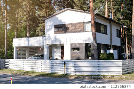 Residential house with a white painted exterior, parked car, and a neat green lawn Residential house with a white painted exterior, parked car, and a neat green lawn 112566874