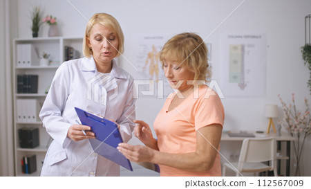 A female physician explains medical test results to a senior patient, aiding in diagnostics 112567009