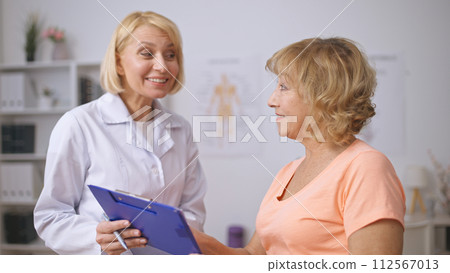 A physiatrist makes a favorable prognosis for a happy female patient after successful treatment A physiatrist makes a favorable prognosis for a happy female patient after successful treatment 112567013