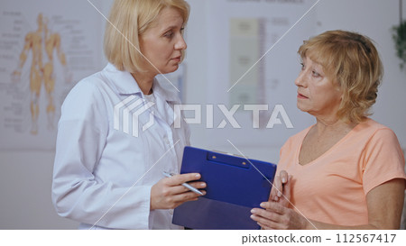 A professional physiatrist makes a prognosis for a senior female patient, outlining her treatment 112567417
