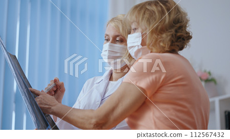 A doctor explains x-ray image test results to a patient, diagnosing pneumonia A doctor explains x-ray image test results to a patient, diagnosing pneumonia 112567432