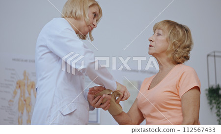 A traumatologist removes a cast from a patient's arm, revealing a healed hand, signifying recovery A traumatologist removes a cast from a patient's arm, revealing a healed hand, signifying recovery 112567433
