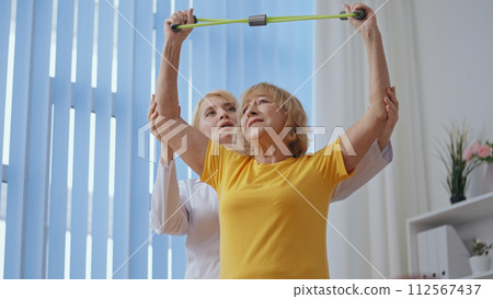 A senior woman does exercises under a physiatrist's supervision, focusing on rehabilitation A senior woman does exercises under a physiatrist's supervision, focusing on rehabilitation 112567437