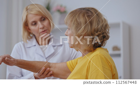 A female physician examines her patient's arm, addressing trauma disorders and providing pain relief 112567448