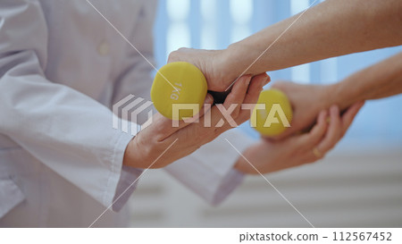 A physiatrist assists her senior patient with an orthopedic exercise, focusing on rehabilitation 112567452