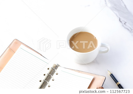 在辦公桌上使用筆記本工作，同時喝加大量牛奶的咖啡或牛奶咖啡。 112567723