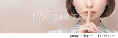 Young oriental woman putting her index finger on her lips 112567822