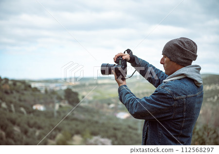 Man photographer capturing beautiful view of mountains on professional camera, photographing the nature wile trekking 112568297