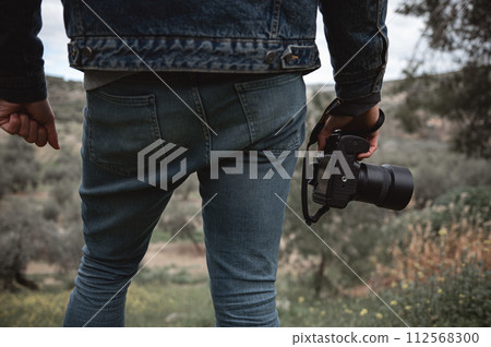 Close-up professional camera in the hands of male traveler photographer 112568300