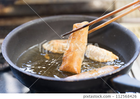 將春捲放入油鍋中煎熟 112568426