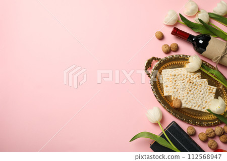 Matzo, bottle of wine, flowers and Torah on pink background, space for text 112568947