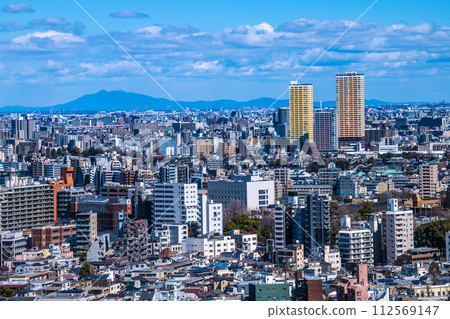 Tokyo cityscape in Japan, overlooking Nippori Station, the tower apartment complex in front of the station (back right), and mountains = March 10th 112569147