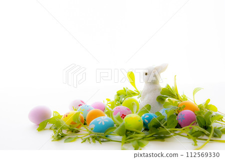 Colorful Easter eggs and cute bunny figurines lying in the weeds 112569330
