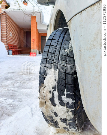 View of the tread of a winter car tire with adhered snow. View of the tread of a winter car tire with adhered snow. 112572986