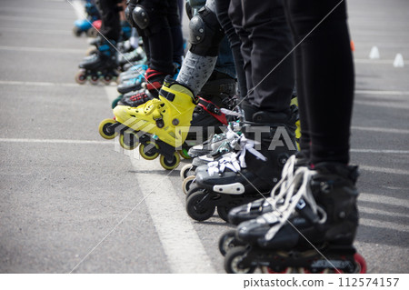 Close up view of wheels befor skating.Legs in rollskikovye skates are lined up in a row Close up view of wheels befor skating.Legs in rollskikovye skates are lined up in a row 112574157
