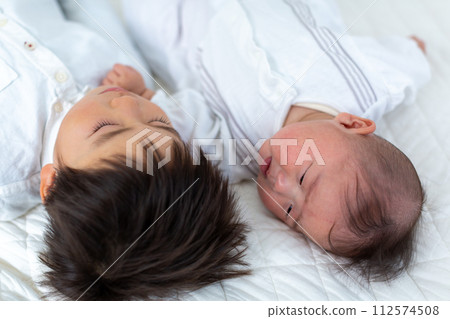 Two infants and an infant taking a nap 112574508