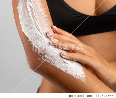 Woman smearing moisturizing body lotion on her arm Woman smearing moisturizing body lotion on her arm 112574667