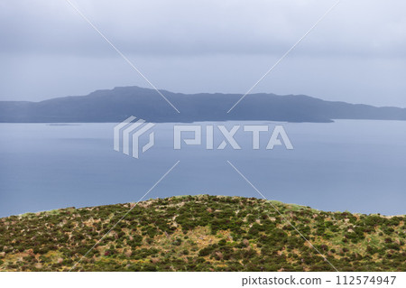 A serene expanse of sea merges with the hazy Raasay Island under a soft grey sky, Isle of Skye 112574947