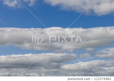 Sky adorned with layers of cumulus clouds, bathed in a soft light blue radiance extending to horizon Sky adorned with layers of cumulus clouds, bathed in a soft light blue radiance extending to horizon 112574962