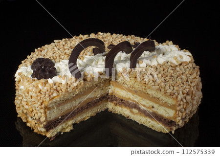 A piece of shortcake cake covered with peanuts on a dark background 112575339