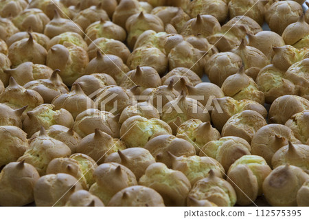 Blanks for filling eclairs. The custard cakes. A lot of baking Blanks for filling eclairs. The custard cakes. A lot of baking 112575395