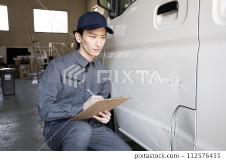 A worker giving an estimate for repairing a damaged car 112576455