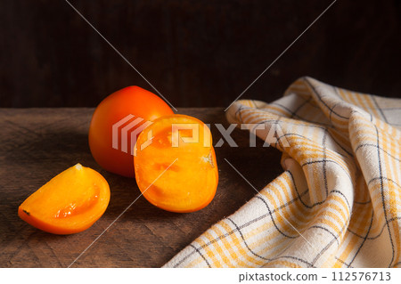 Cut and whole of yellow tomato and yellow towel on wooden background.. Cut and whole of yellow tomato and yellow towel on wooden background.. 112576713